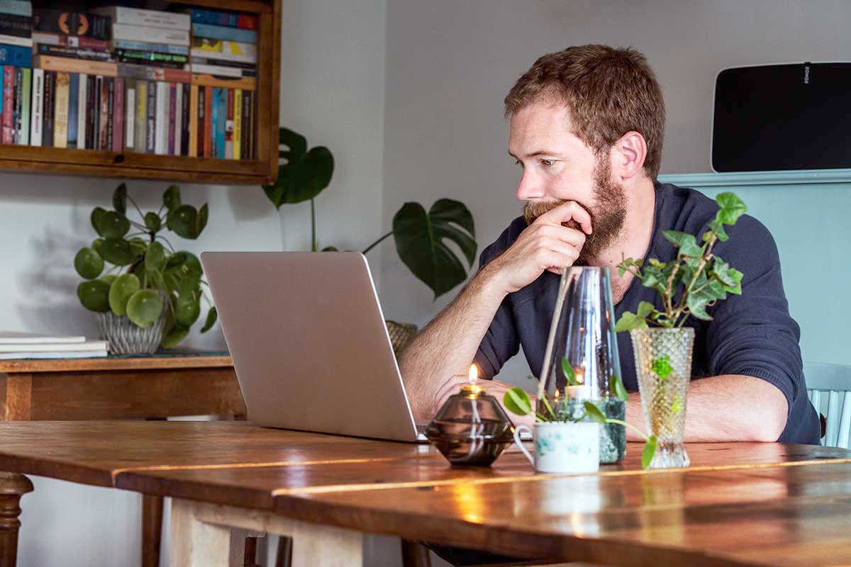 Mann sitter med laptop, til illustrasjon for nettsikkerhet og kortbruk