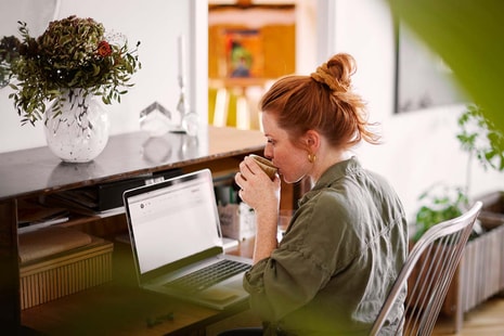 Dame sitter ved kontorpult og jobber på en PC, til illustrasjon for betale til utland