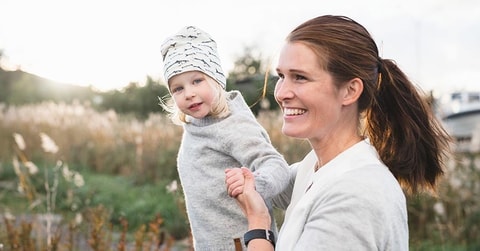 Kvinne og barn leker ute i gresset, til illustrasjon for budsjett til familie