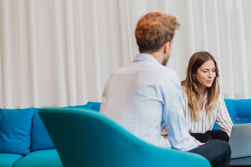 Mann sitter på en stol og en kvinne sitter i en sofa med en PC fremfor seg, til illustrasjon for serielån