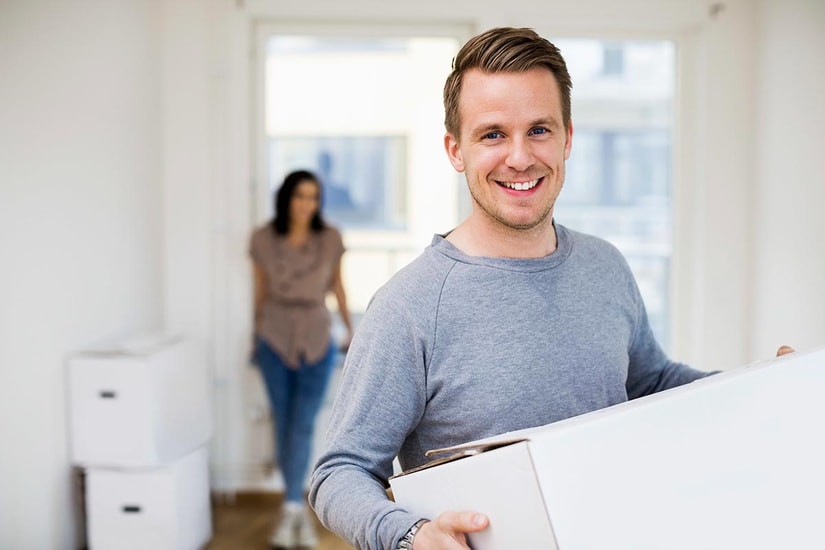 Mann står i en bolig og holder en flyttekasse, til illustrasjon for overtakelse av bolig