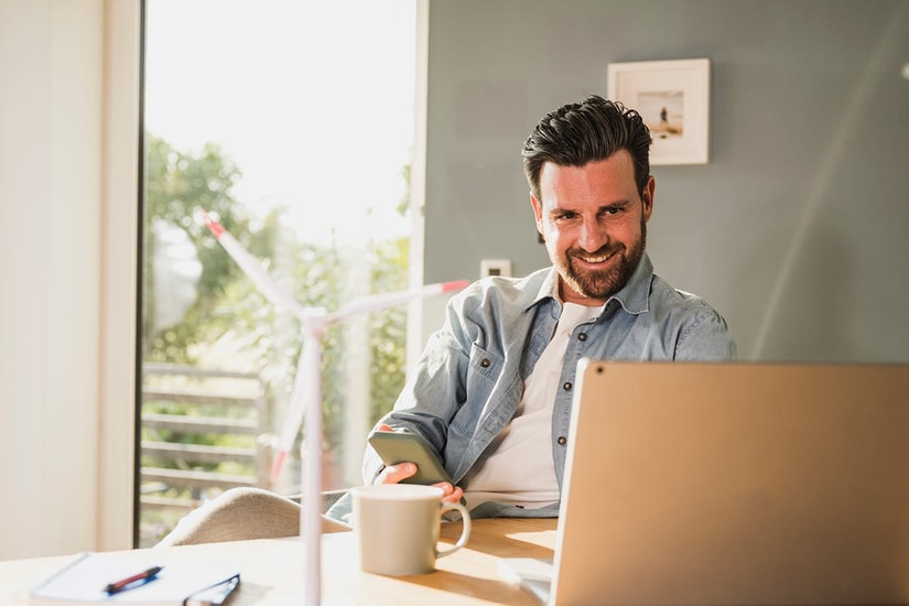 Mann sitter med pc på kjøkkenbordet, til illustrasjon for når kommer renter inn på konto