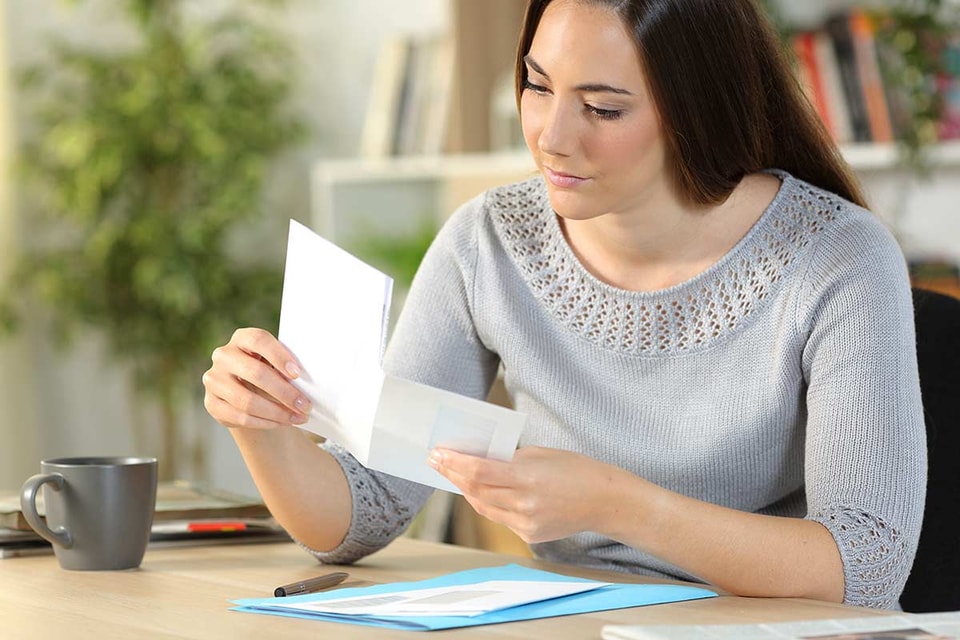 Dame sitter ved kontorpult og holder på en brevgiro