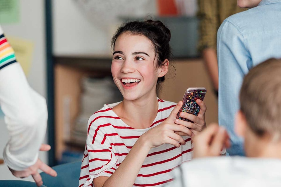 Ung jente holder en mobiltelefon, til illustrasjon for BankID for ungdom