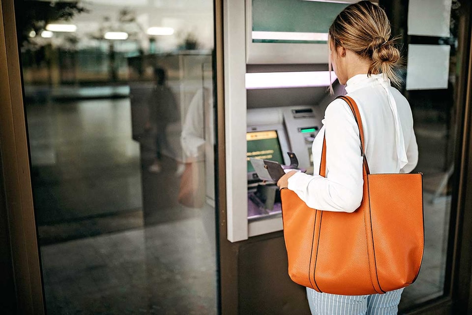 Dame tar ut penger i minibank - illustrasjon for lokal valuta