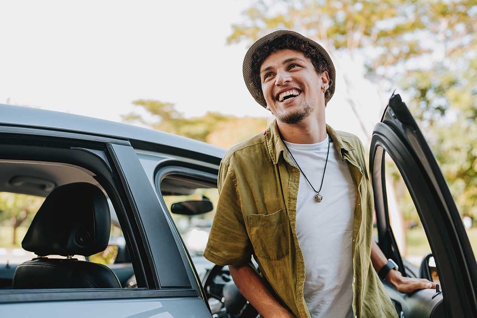Mann smiler mens han går ut fra en bil, til illustrasjon for billån