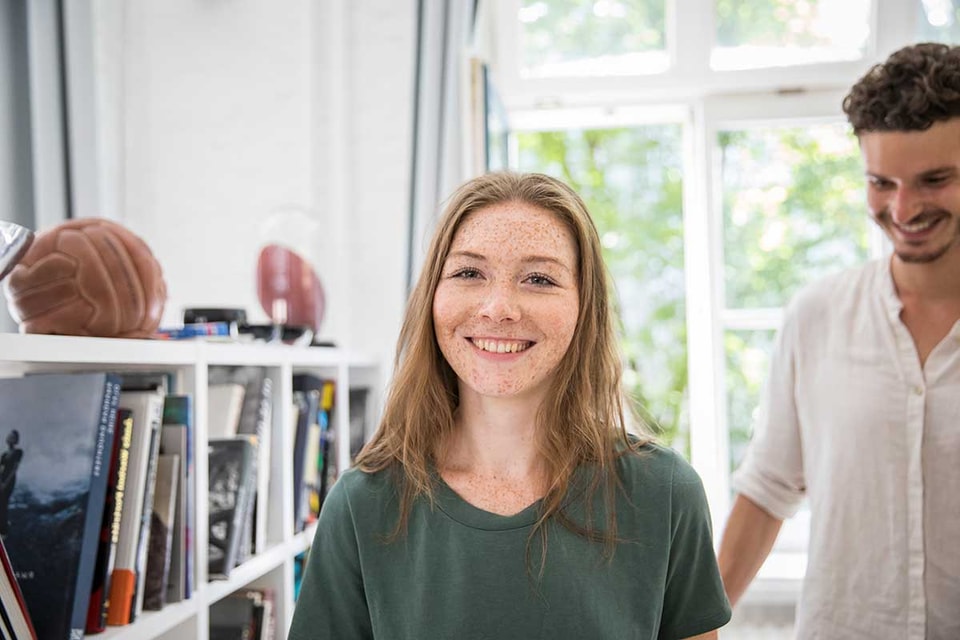 Jente står i leilighet og smiler mens en mann er bak henne, til illustrasjon for medlåntaker