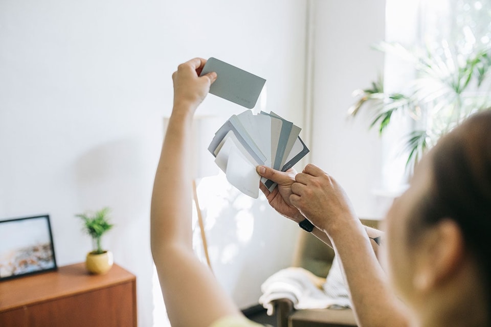 Dame ser på fargerpøver mot vegg, til illustrasjon for tips til oppussing