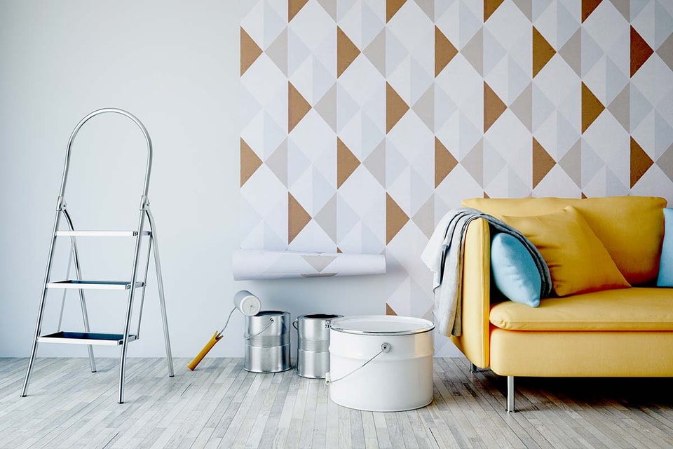 Gul sofa med tapet på veggen og malespann på gulvet, til illustrasjon for å øke boliglån for oppussing