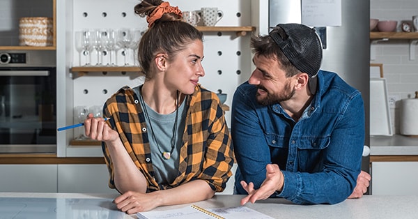 Kvinne og mann står på kjøkkenet og går gjennom en sjekkliste som ligger på bordet