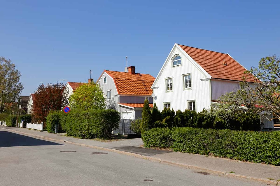 Flere boliger i en gate med store hekker, til illustrasjon for refinansiere boliglånet