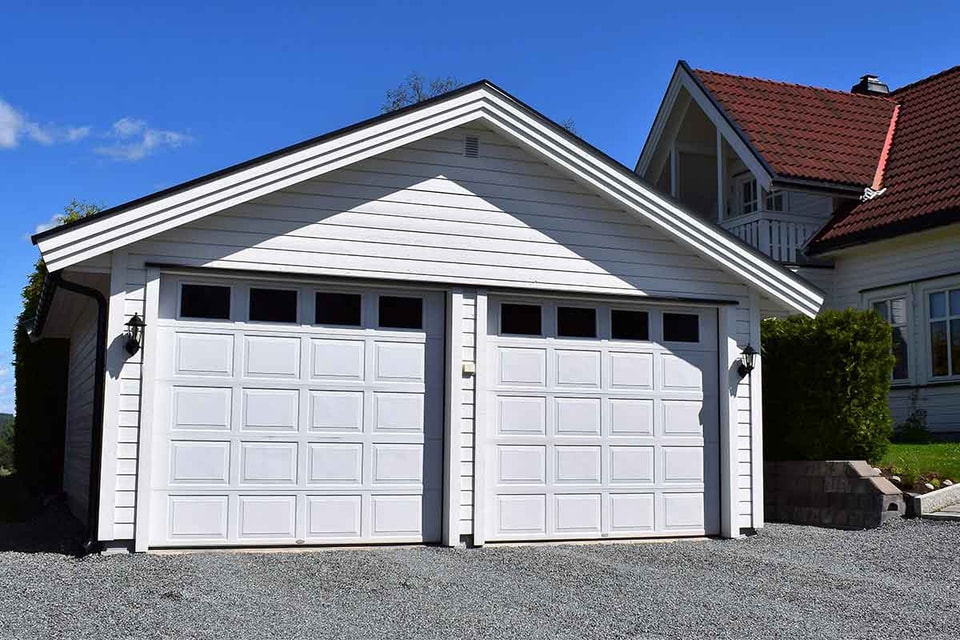 Dobbeltgarasje fremfor hvitt hus, til illustrasjon for bygge garasje