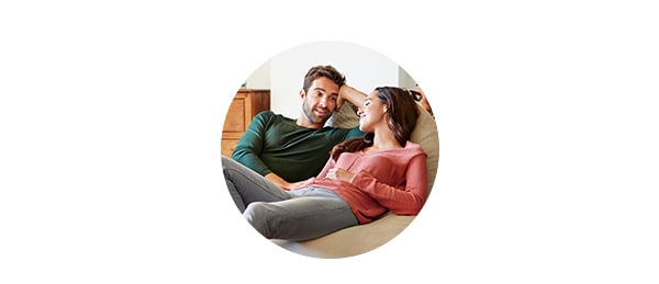 Par ligger på sofaen og snakker om felles økonomi