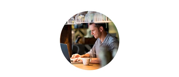 Mann sitter på kafé og jobber på PC, til illustrasjon for mobil og nettbank