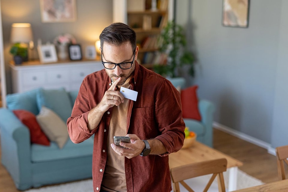 Mann ser mistenksom på mobiltelefonen og lurer på om det er fakturasvindel