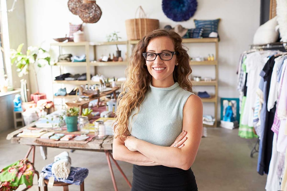 Dame står med armene i kors og viser frem sin butikk, til illustrasjon for selskap under stiftelse