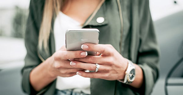 Dame som skriver på mobil, til illustrasjon for svindel på e-post og sms