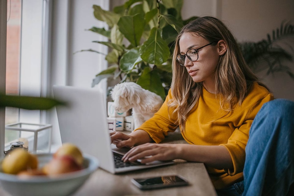 Kvinne sitter med laptop og jobber, til illustrasjon for å unngå skattesmell