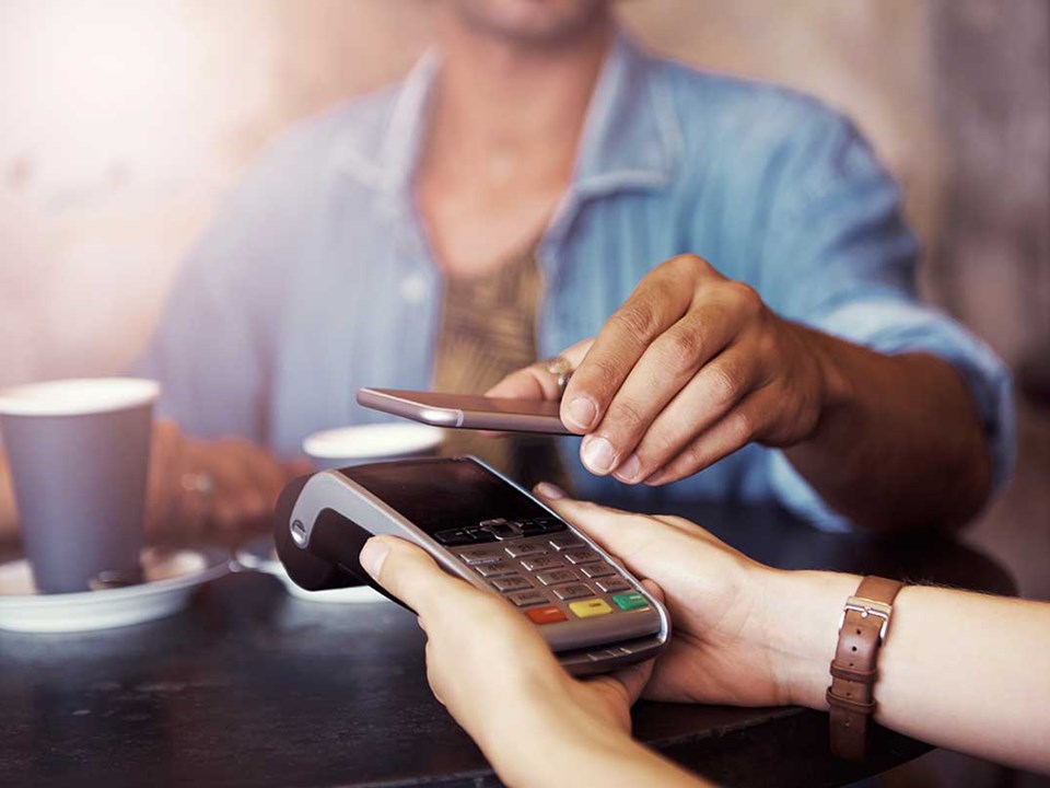 Kvinne på kafé betaler med samsung pay på mobilen