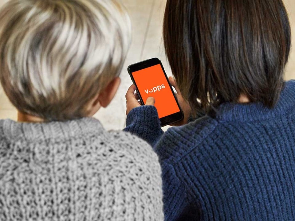 To barn sitter på gulvet og ser på telefonen mens de utforsker Vipps sammen