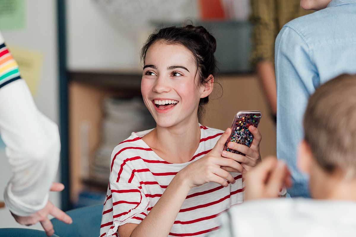 Ung jente holder en mobiltelefon, til illustrasjon for BankID for ungdom