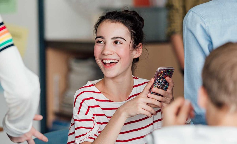 Ung jente holder en mobiltelefon, til illustrasjon for BankID for ungdom