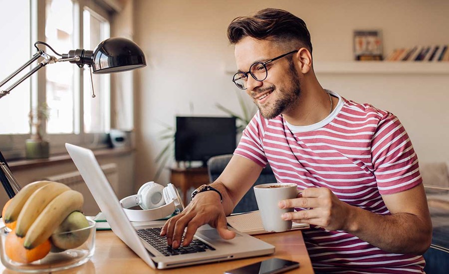 Mann drikker kaffe og ser på pc, til illustrasjon for brukskonto
