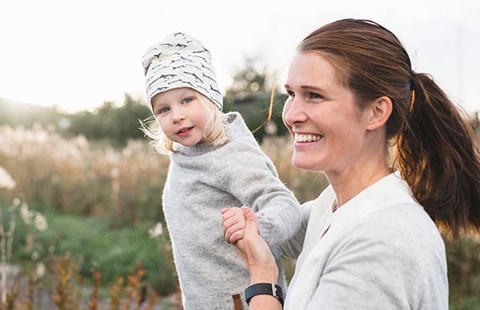 Kvinne og barn leker ute i gresset, til illustrasjon for budsjett til familie