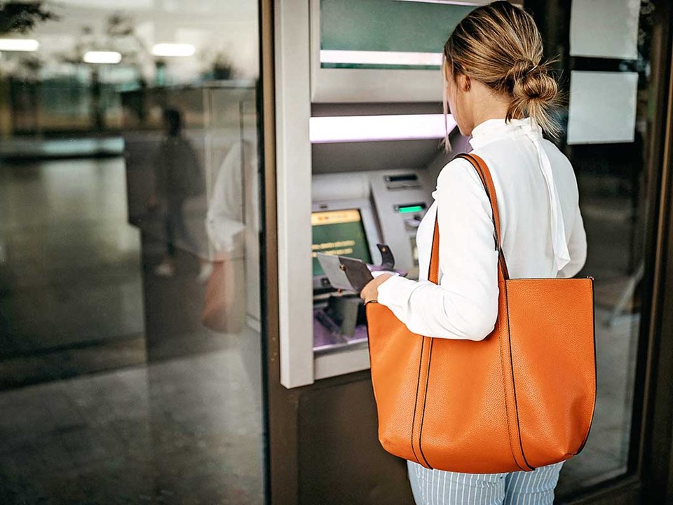 Dame tar ut penger i minibank - illustrasjon for lokal valuta