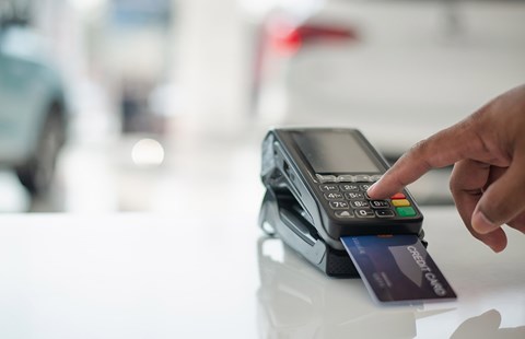 Mann bruker bankterminal til å sette inn penger i butikk