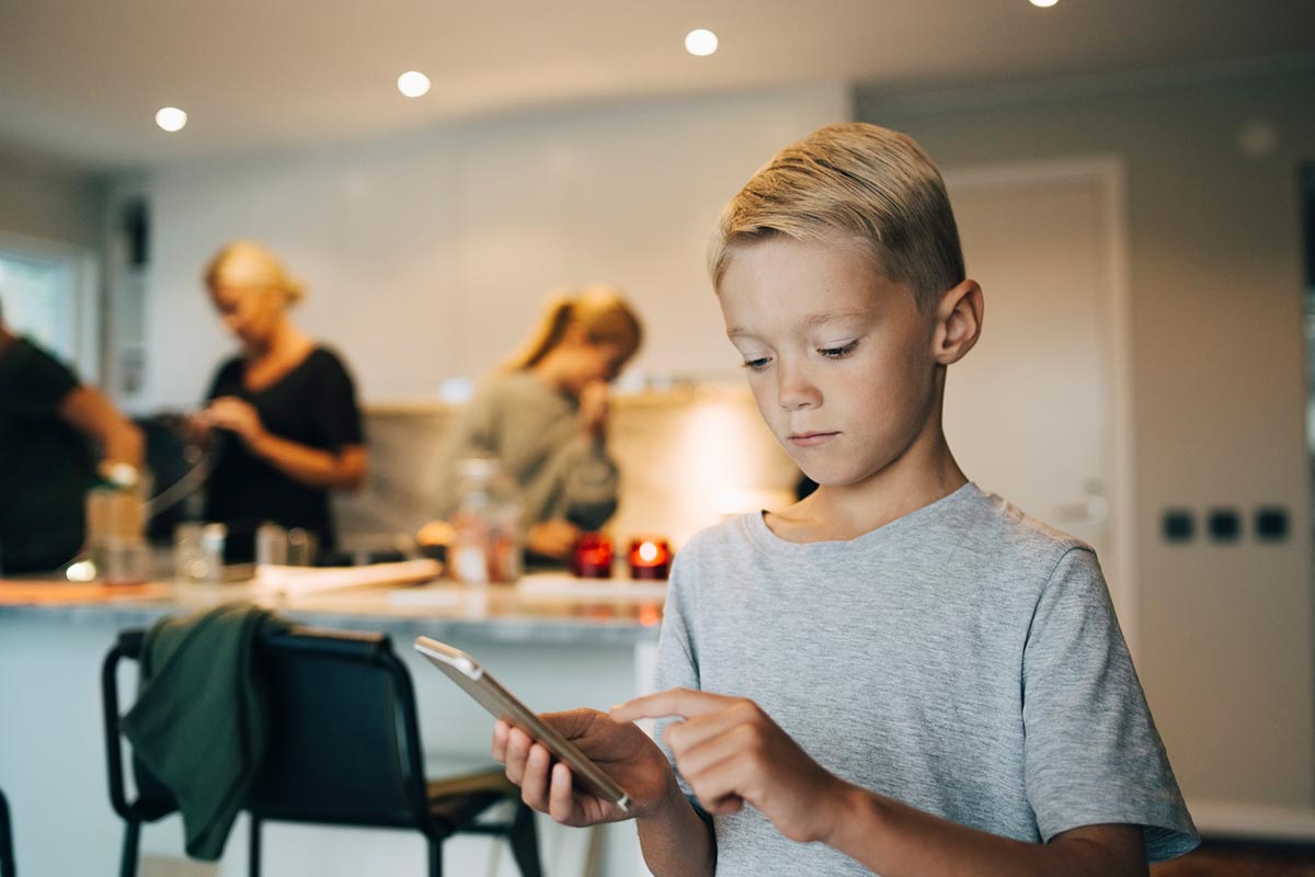 Gutt ser på mobiltelefonen sin, til illustrasjon for mine kort appen til barn