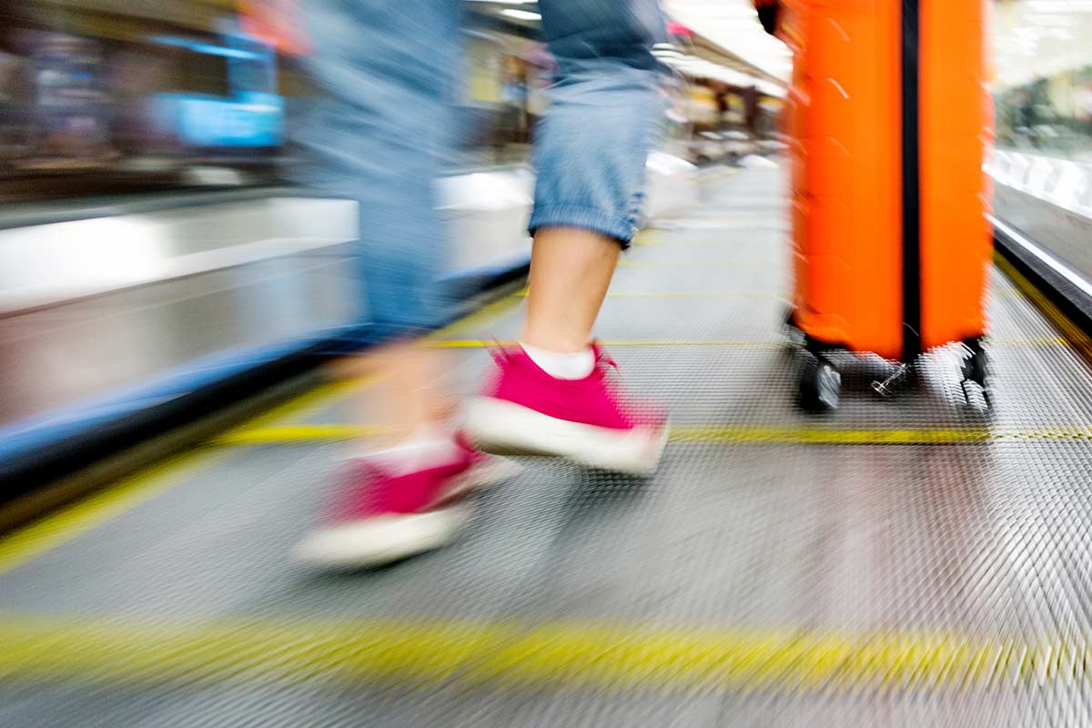 Dame i rulletrapp med koffert, til illustrasjon for trygt med to kort