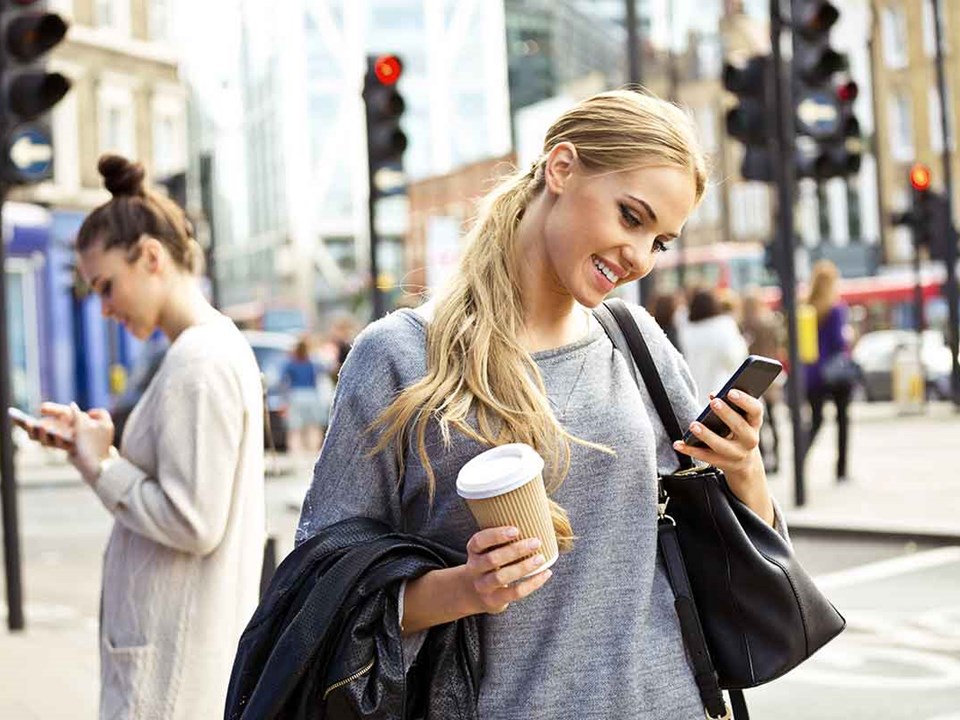 Jente i byen med kaffe og mobil - illustrasjon for BankID