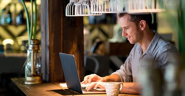 Mann på kafé jobber på laptop