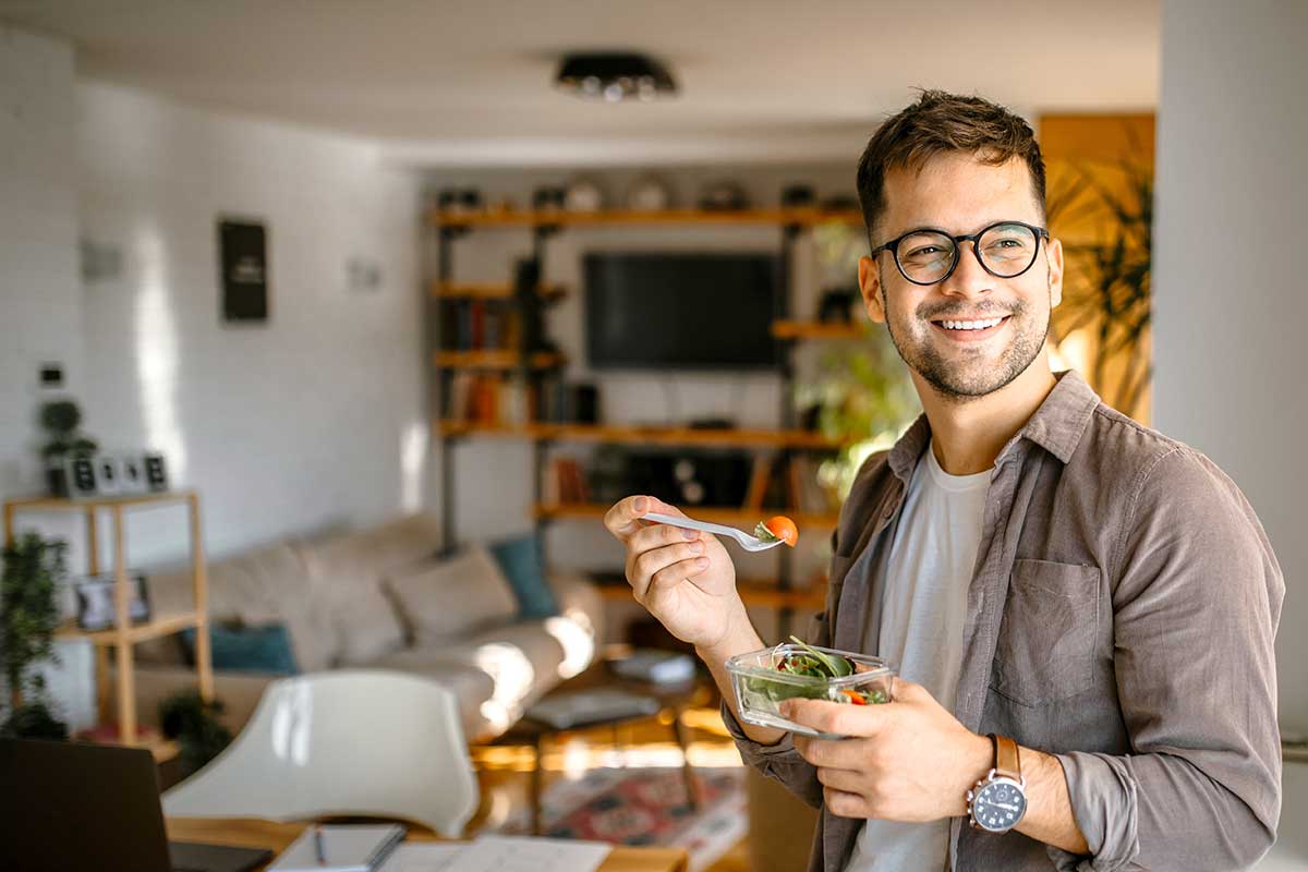 Mann er hjemme og og spiser en salat, illustrasjon til lønnskonto