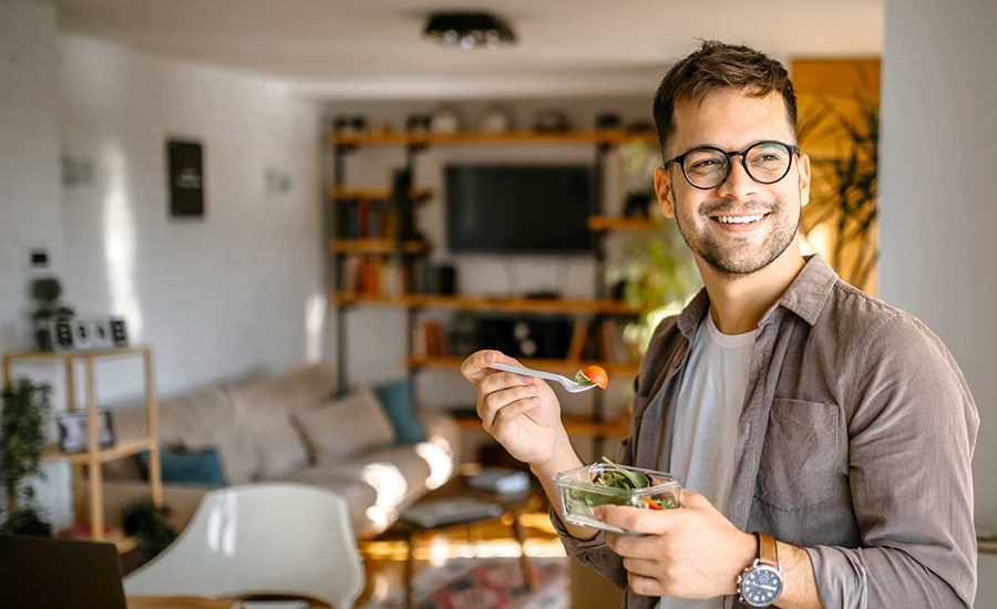 Mann er hjemme og og spiser en salat, illustrasjon til lønnskonto