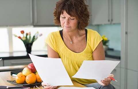 Dame ved kjøkkenbenken leser dokumenter, til illustrasjon for lånetyper