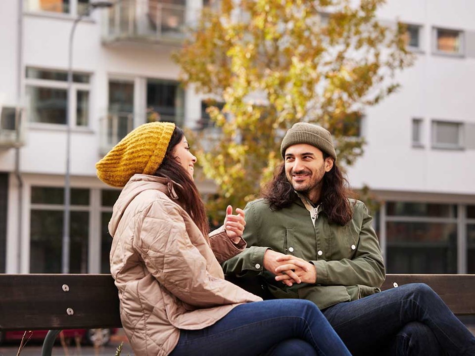 Kvinne og mann sitter ute på en benk, til illustrasjon for rammelån vs boliglån