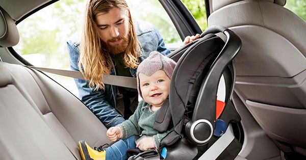 Mann putter barn i bilsete i ny bil