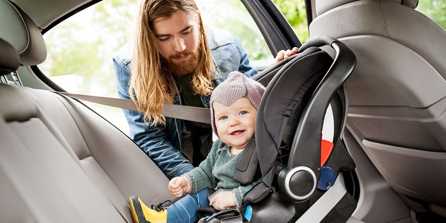 Mann putter barn i bilsete i ny bil, til illustrasjon for billån