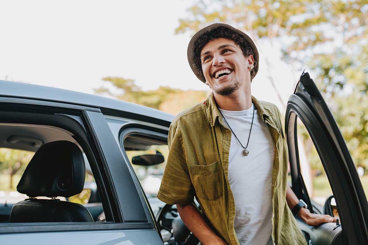Mann smiler mens han går ut fra en bil, til illustrasjon for billån