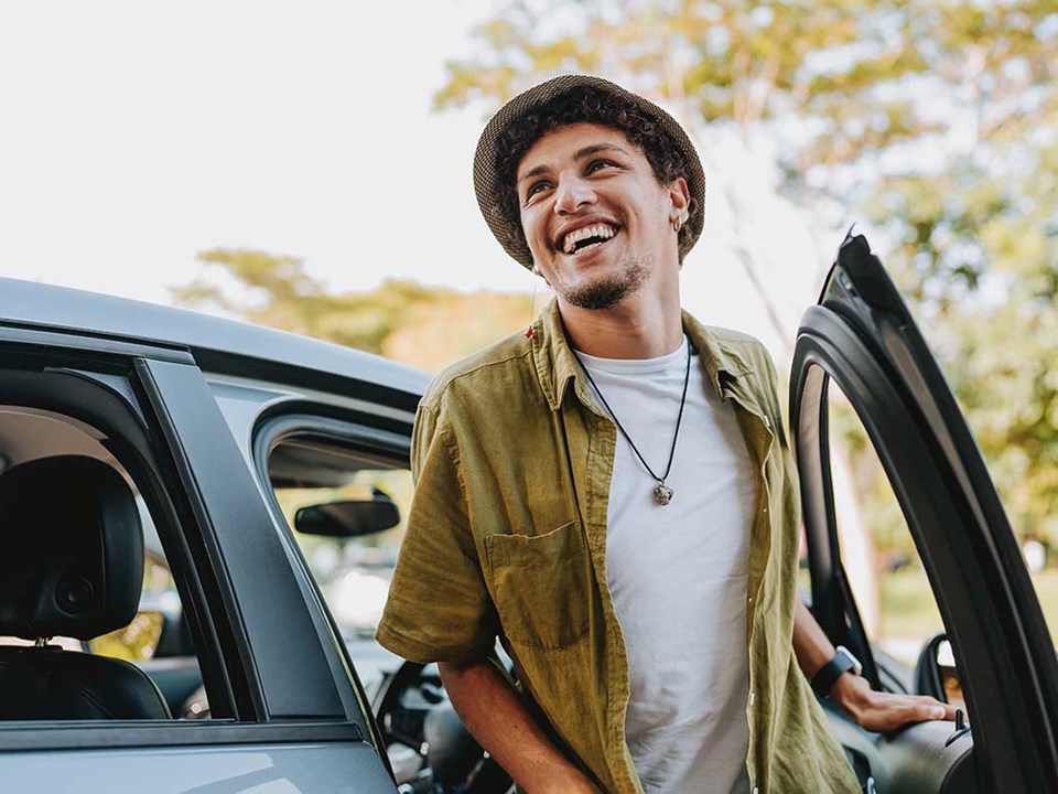 Mann smiler mens han går ut fra en bil, til illustrasjon for billån