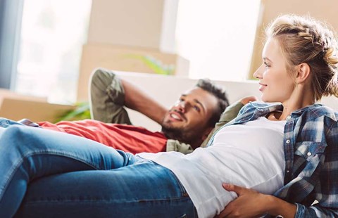 Jente prater med person om ulike lånetyper Par slapper av i sofaen, til illustrasjon for annuitetslån vs serielån