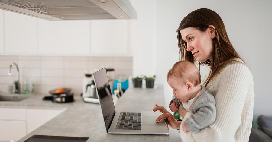 Kvinne med barn på fanget bruker datamaskin, til illustrasjon for kunde som søker boliglån