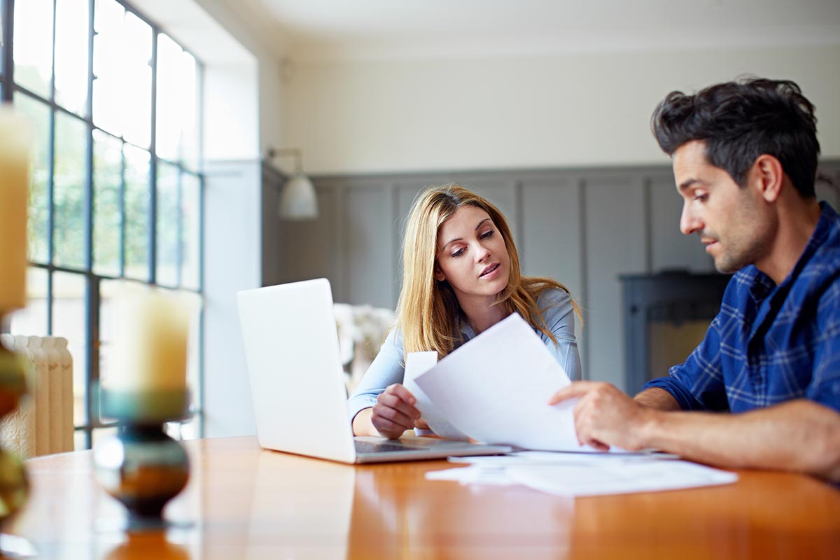 Dame og mann sitter ved et bord og leser dokumenter, til illustrasjon for bytte bolig