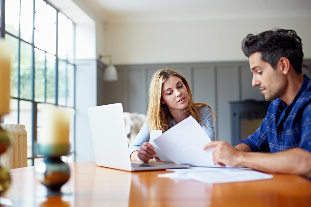 Dame og mann sitter ved et bord og leser dokumenter, til illustrasjon for bytte bolig