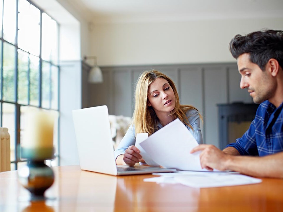 Dame og mann sitter ved et bord og leser dokumenter, til illustrasjon for bytte bolig