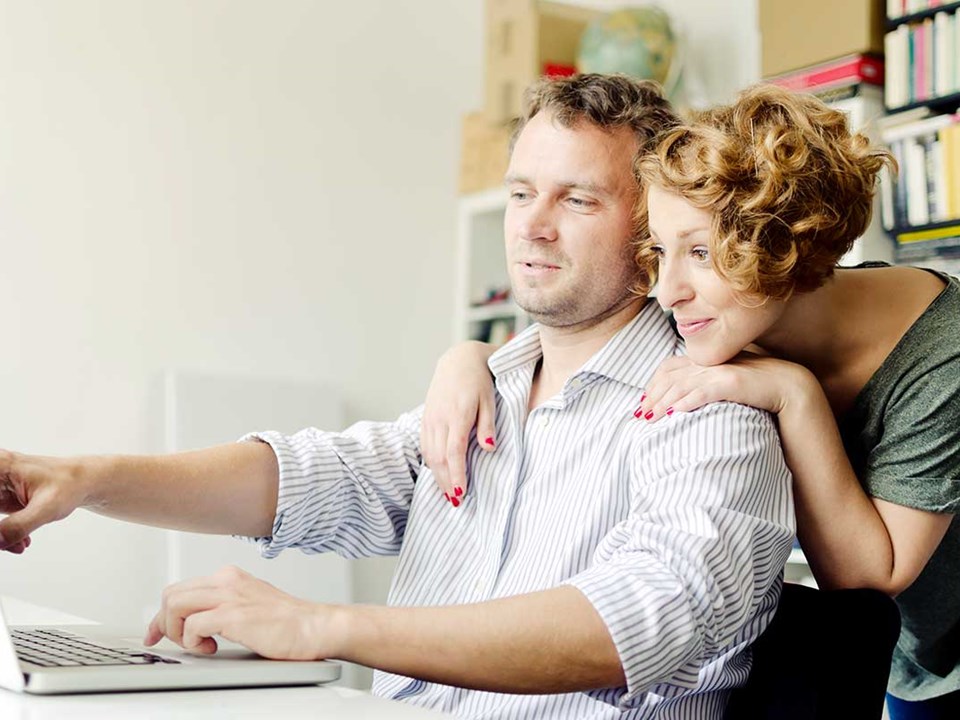 En mann peker på en skjerm med en dame bak seg, til illustrasjon for finansieringsbevis