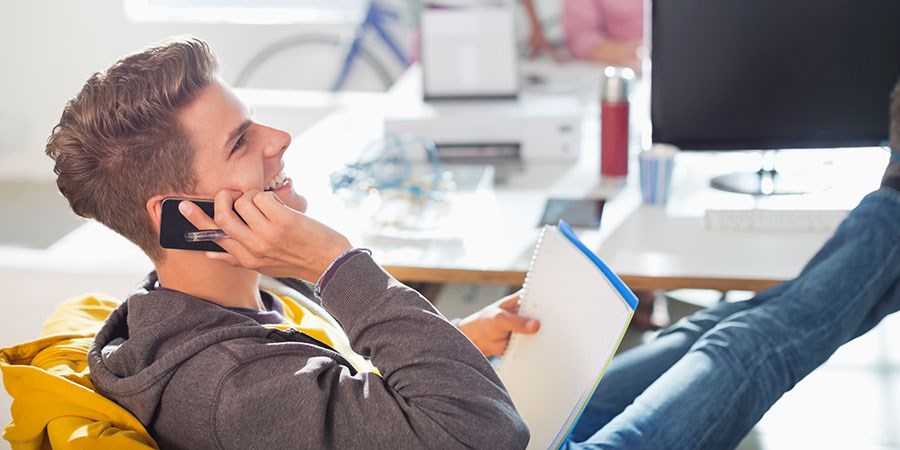 Ung gutt sitter i telefonen og snakker om budrunde