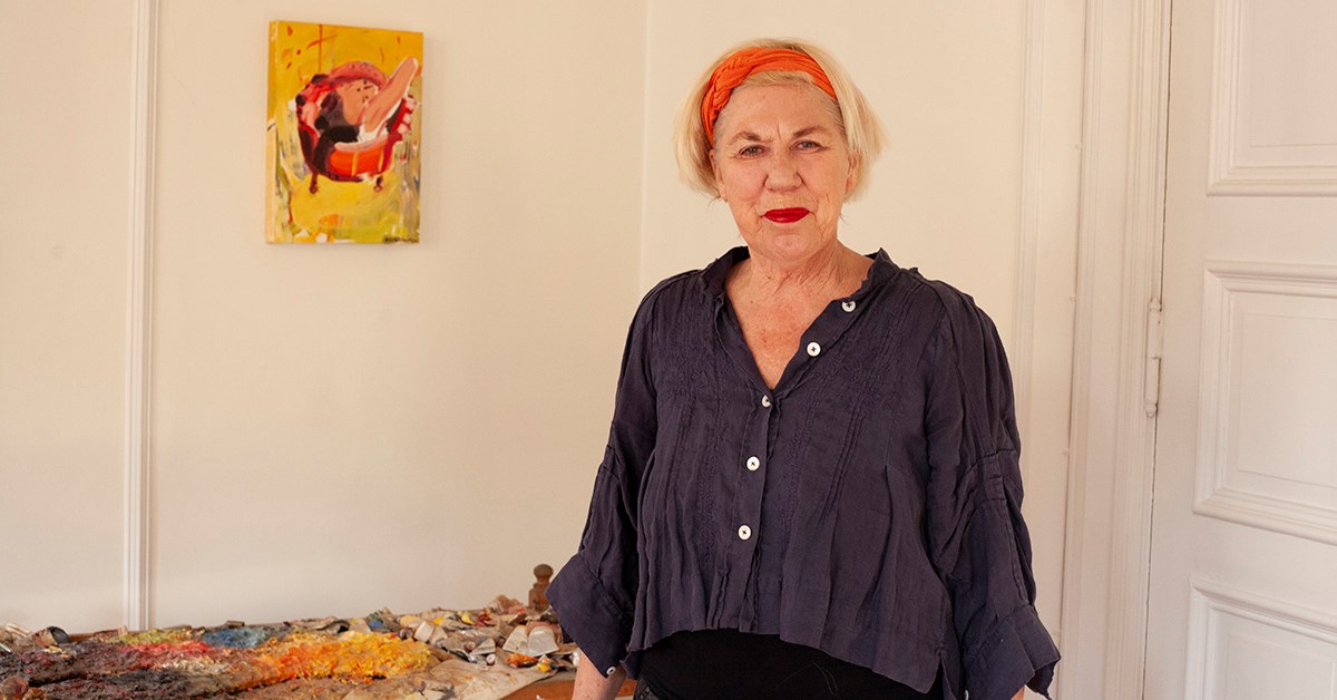 Bente er SeniorLånskunde i BN Bank og står i sitt eget hjem med fargerikt bilde bak, til illustrasjon for SeniorLån